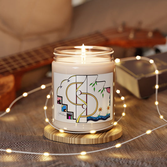 A lit white candle in a clear glass jar sits on a round wooden coaster, surrounded by warm white string lights. The jar features a colorful graphic label with abstract gold lines, green leaves, and small pink and blue details.